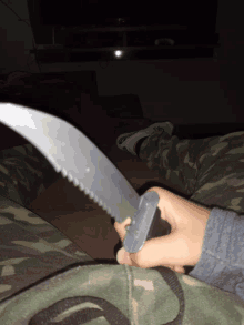 a person in camouflage pants is holding a plastic knife in their hand