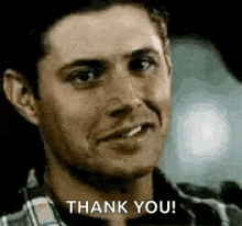 a man in a plaid shirt is smiling and says `` thank you '' .