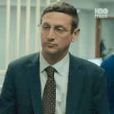a man in a suit and tie with a hbo max logo in the background