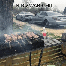 a bottle of water sits on a table next to a grill with cars in the background