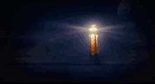 a lighthouse is lit up in the dark with a moon in the background