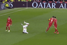 a group of soccer players on a field with a qatar advertisement in the background