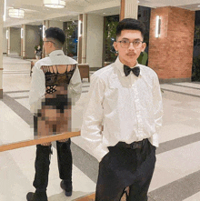 a man in a white shirt and bow tie stands in a hallway