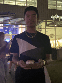 a man holding a sandwich in front of a store that says optique