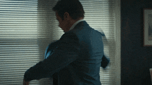 a man in a suit is standing in front of a window