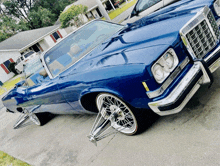 a blue car is parked in a driveway with chrome wheels