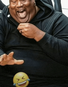 a man in a black shirt is laughing with a yellow smiley face on his belly