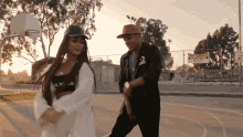 a man and a woman are dancing on a basketball court in front of a sign that says no glasses