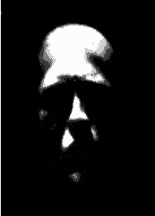 a black and white photo of a person 's face in the dark .