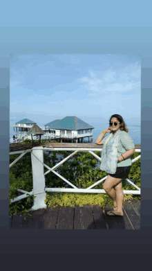 a woman stands on a wooden deck in front of a house