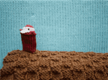 a small knitted santa is standing on a knitted surface