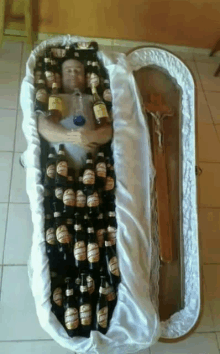 a man is laying in a coffin filled with beer