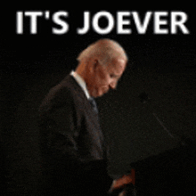 a man in a suit and tie stands at a podium with the words it 's joever behind him