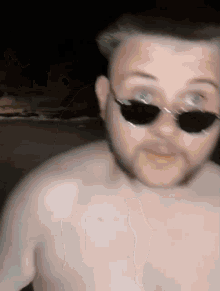 a man without a shirt is wearing sunglasses and looking at the camera