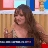 a woman is sitting in front of a sign that says lo que pasa en la casa