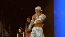 a man without a shirt is dancing on a stage with a woman watching