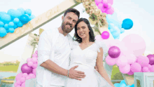 a man and a pregnant woman are posing for a picture in front of balloons and a sign that says baby girl