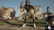 a man wearing zebra print shorts is dancing in front of a house .