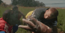 a group of men are doing push ups in a field with a hand reaching out to help them .