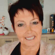 a woman smiles in front of a dresser with a picture of a man on it