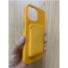 a person is holding a yellow phone case with a card holder on it