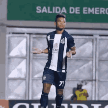 a soccer player with the number 71 on his shorts is standing in front of a sign that says salida de emergencia