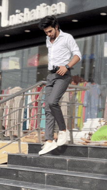 a man wearing a white shirt and grey pants is walking down a set of stairs