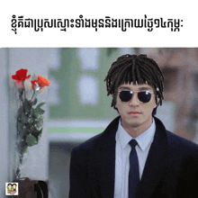 a man with dreadlocks wearing sunglasses and a suit stands in front of a vase of flowers