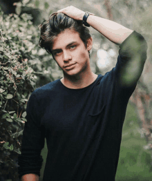 a young man with a watch on his wrist holds his hair