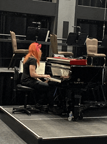 a woman playing a yamaha grand piano on a stage