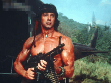 a shirtless man is holding a gun in a field