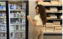 a woman stands in front of a refrigerator full of milk