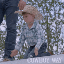 a little boy wearing a cowboy hat is kneeling on a fence with the cowboy way written in the corner