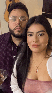 a man and a woman pose for a picture with a guitar behind them