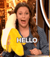 a woman holding a stuffed banana with the word hello written on it