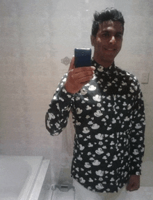 a man in a mickey mouse shirt takes a selfie with his phone