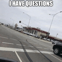 a car is driving down a street with a sign that says `` i have questions '' on it .