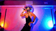 a woman is singing into a microphone with a disco ball on her head
