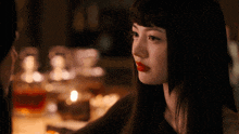 a woman with red lipstick looks at another woman in a dark room