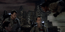 a group of men in ghostbusters uniforms are standing in front of a city at night