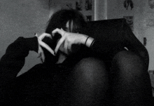 a woman is sitting in a chair making a heart shape with her hands