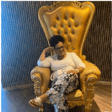 a woman is sitting in a gold chair holding a purse .