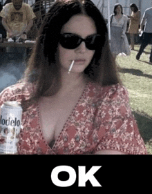 a woman is smoking a cigarette and drinking a can of beer .