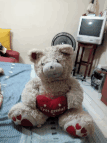 a teddy bear sitting on a bed holding a heart that says eres genial