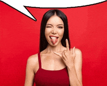 a woman in a red tank top is sticking her tongue out and making a rock sign .