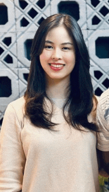 a woman with long black hair wearing a white sweater smiles for the camera