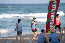 a group of people playing volleyball on a beach with a banner that says teambuilding