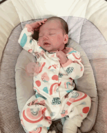 a baby wearing a rainbow onesie is sleeping