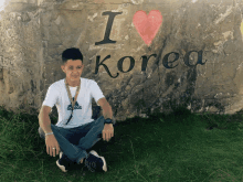 a man is sitting in front of a sign that says i love korea