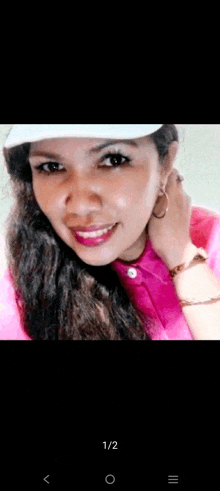 a woman wearing a pink shirt and a white hat smiles for the camera .